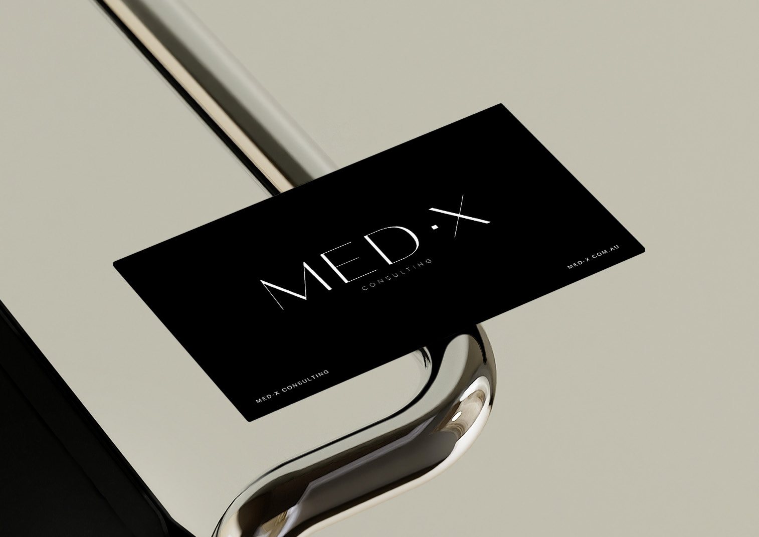 MED·X Consulting business card on a polished chrome surface