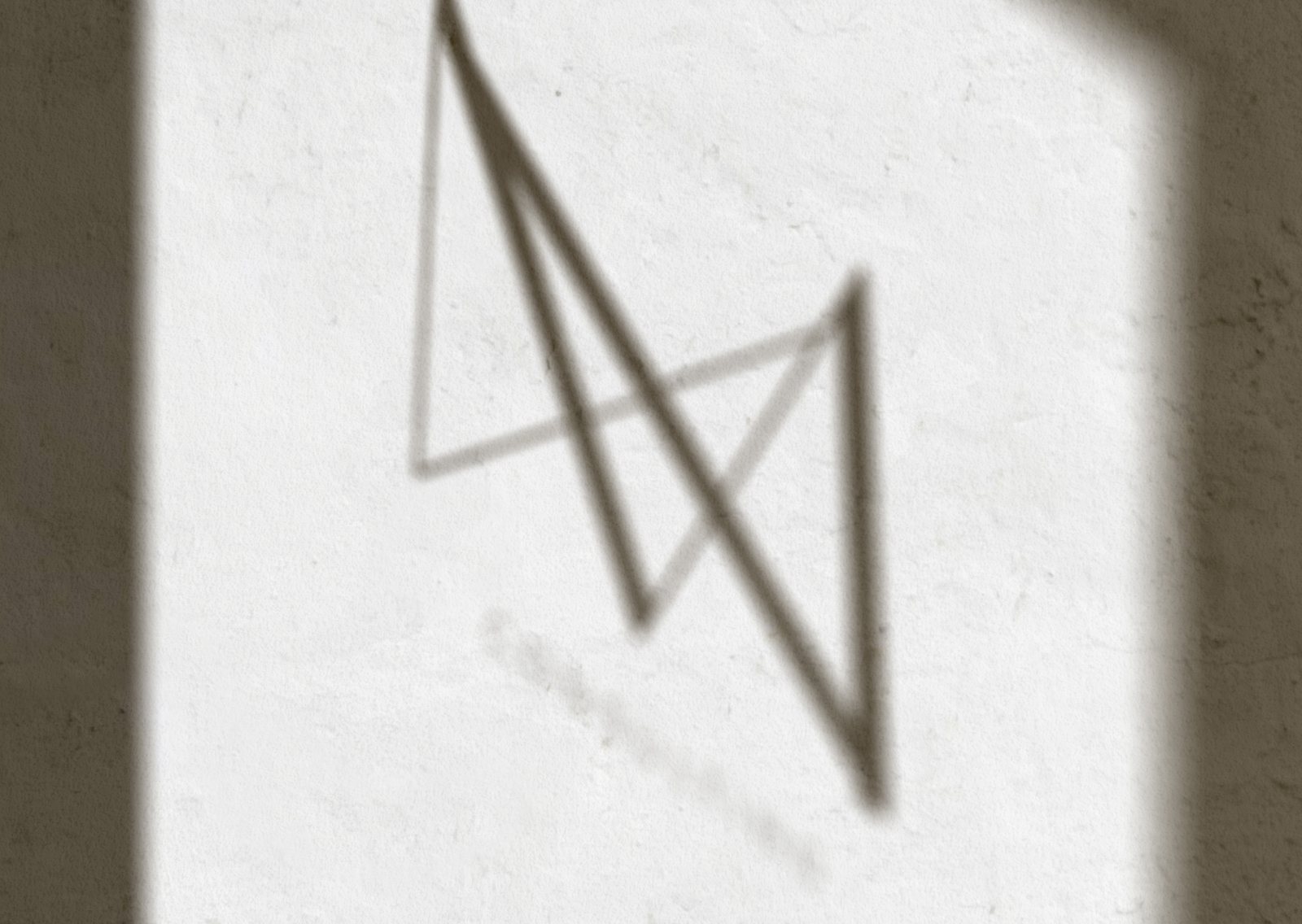 The MED·X submark cast as a soft shadow across a plaster wall
